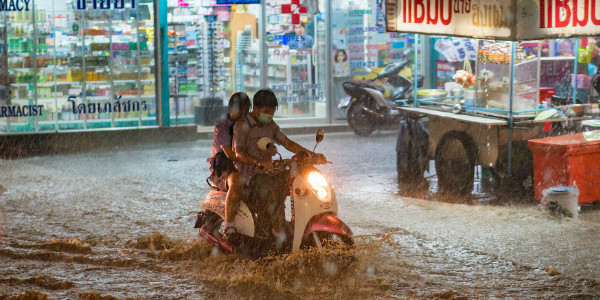a couple outside a pharmacy stuck on a moped during heavy thai floods