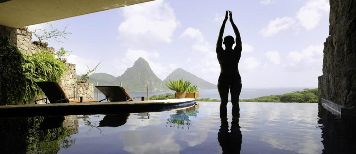 a woman stands in a yoga pose in front of a luxurious indoor pool as a fancy thai resort, representing wellness tourism