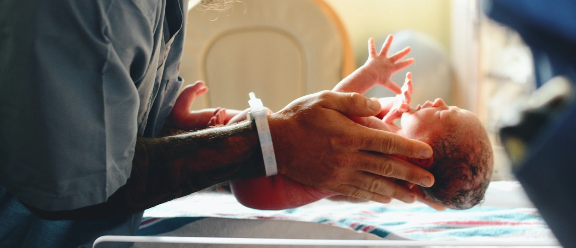 A medical staff holding a baby up from a hospital bed