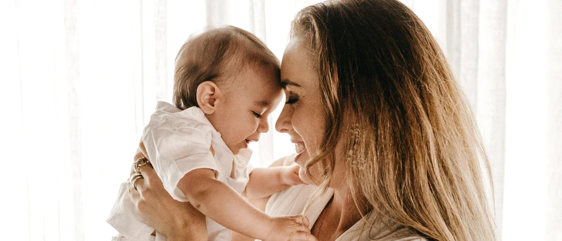 A mother holding a baby and smiling