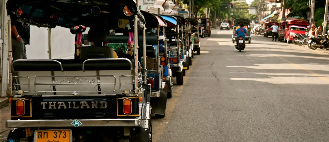 Row of Tuk Tuks in parked along the street in Thailand
