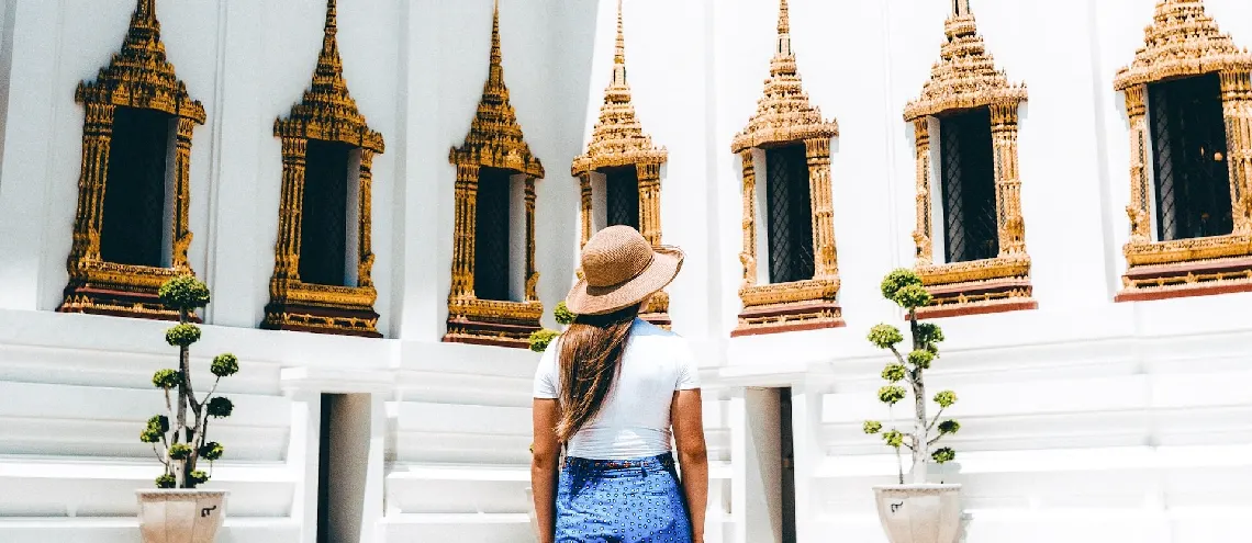 Woman standing looking at a beautiful white temple in Thailand