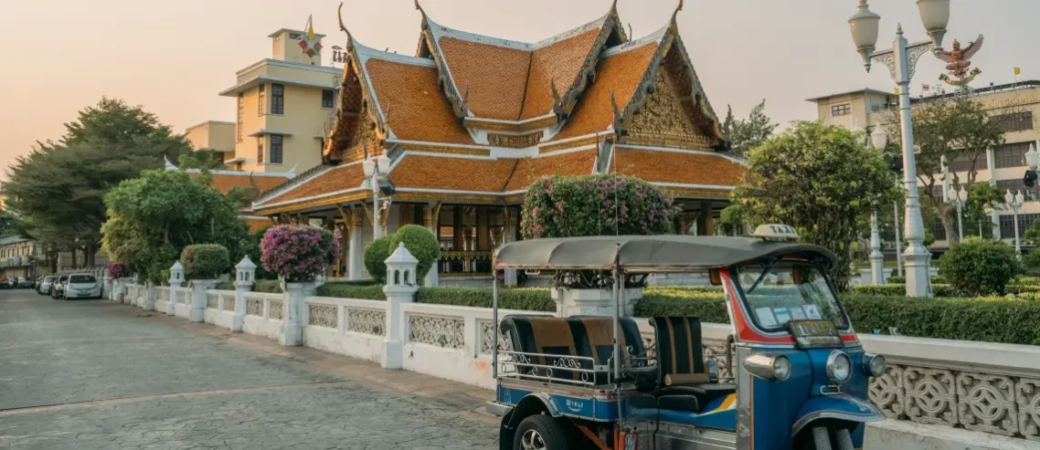 A blue Tuk Tuk parked in front of a temple
