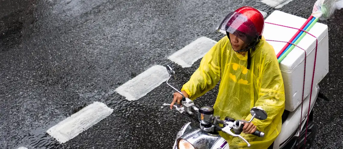 A person riding a motorbike wearing a yellow raincoat