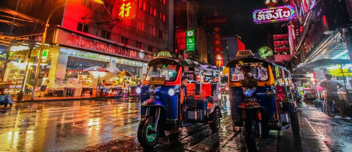 Two tuk-tuks on a wet road of Yaowarat