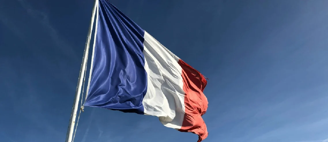 A big French flag under a blue sky